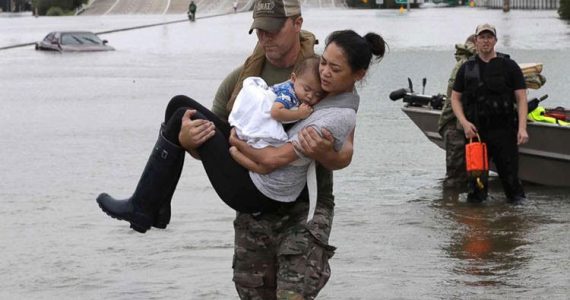 image of man carrying mother and baby, flood victims of hurricane harvey