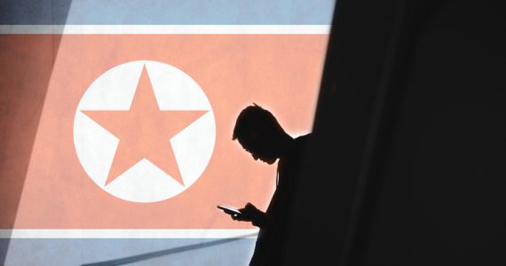 Man holding phone against North Korean flag