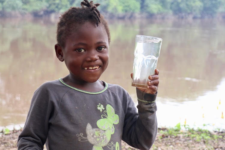 Picture of girl in Cameroon holding glass of clean water