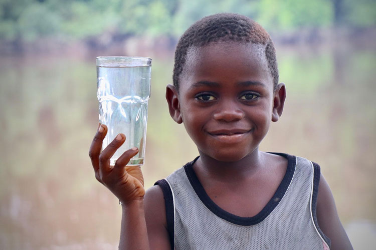 Picture of boy in Africa holding glass of clean water