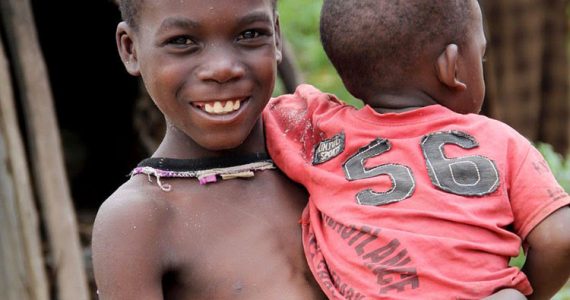 Child in poverty holding little brother and smiling