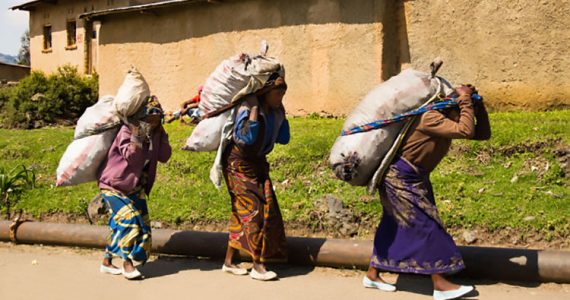 Picture of women in Africa carrying heavy items on their heads and backs